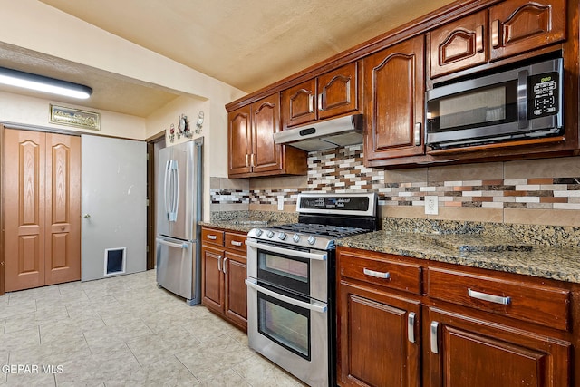 kitchen with appliances with stainless steel finishes, backsplash, stone countertops, and lofted ceiling