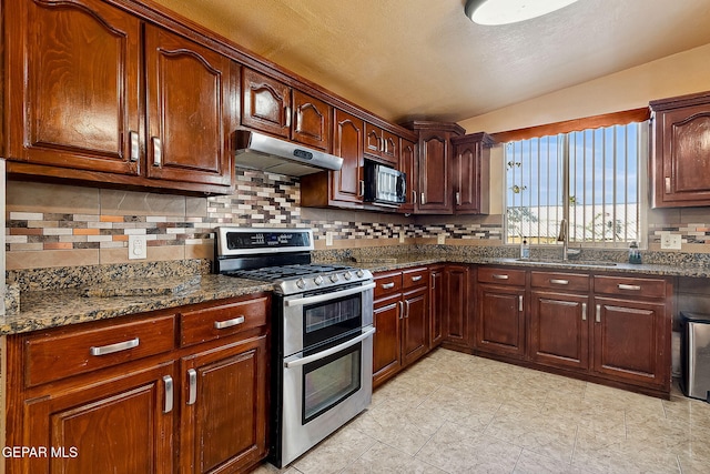 kitchen with decorative backsplash, range with two ovens, dark stone counters, and sink