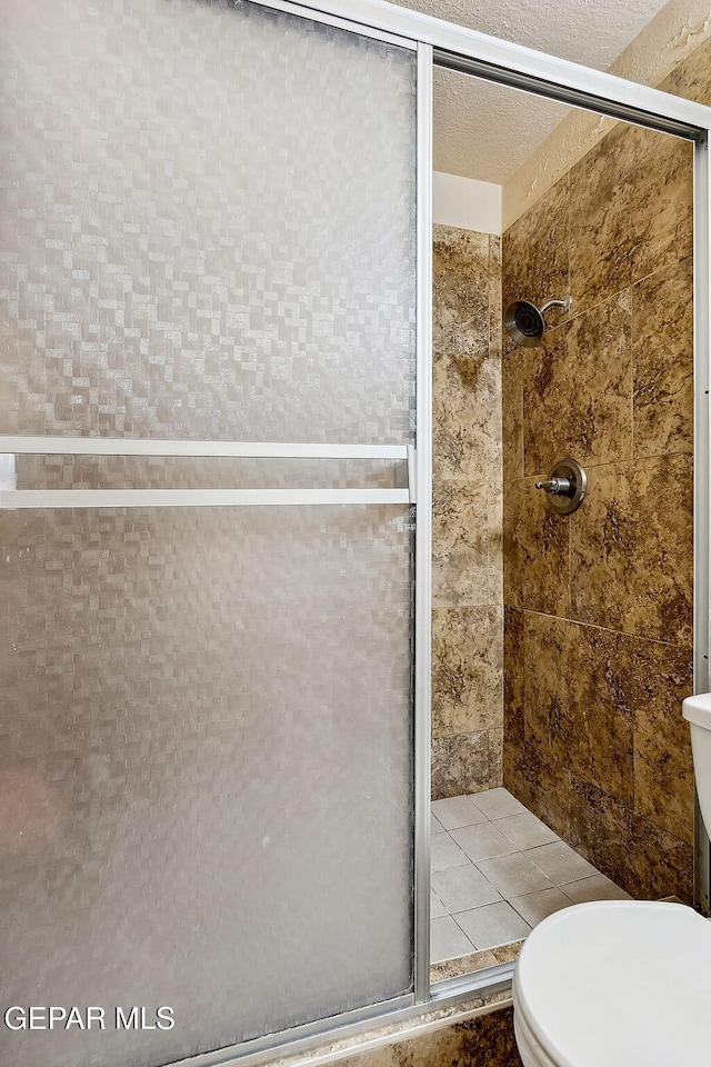 bathroom featuring a textured ceiling, toilet, and walk in shower