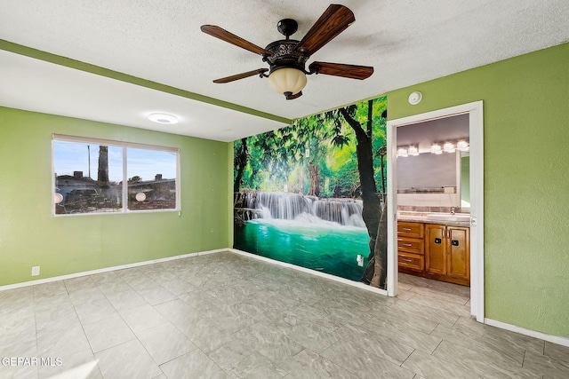 empty room with a textured ceiling, ceiling fan, and sink