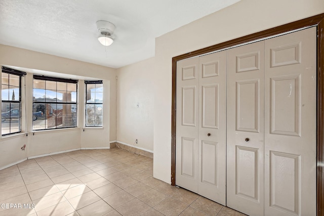 unfurnished bedroom featuring ceiling fan, a closet, and light tile patterned flooring