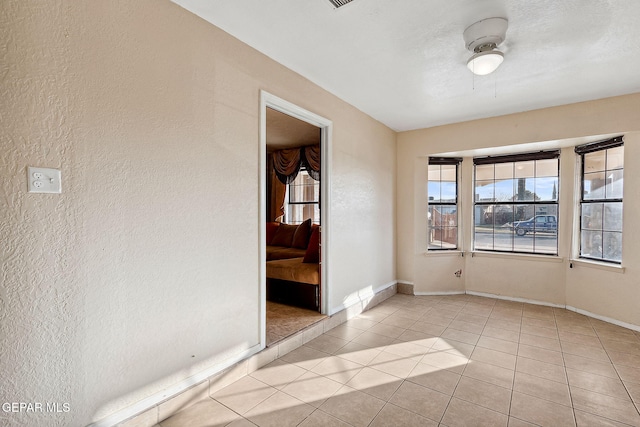 tiled spare room featuring ceiling fan