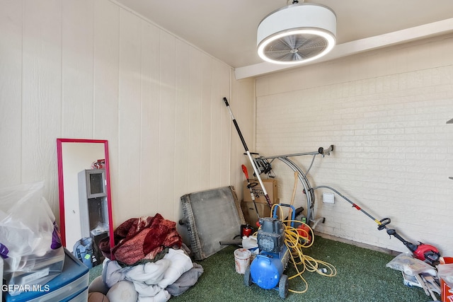 miscellaneous room with carpet flooring, wood walls, and brick wall