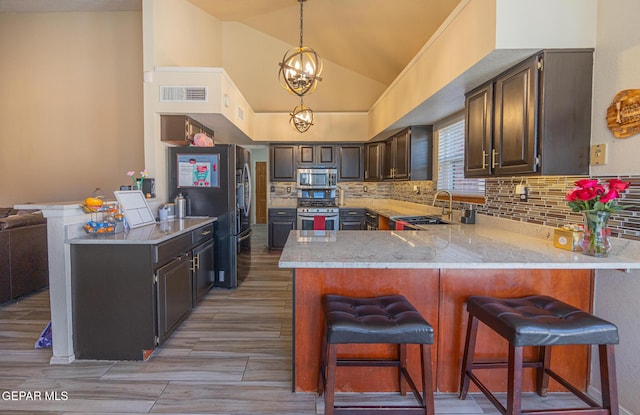 kitchen featuring visible vents, light countertops, appliances with stainless steel finishes, a sink, and a peninsula