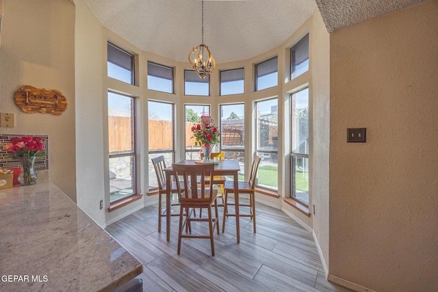 dining area with baseboards, a textured wall, a textured ceiling, and an inviting chandelier