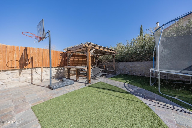 view of yard with a patio area, a fenced backyard, a trampoline, and a pergola