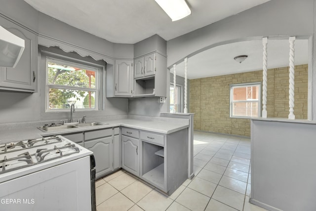 kitchen featuring gray cabinetry, sink, light tile patterned floors, and white gas range oven