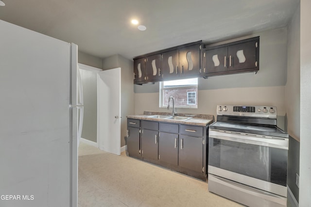 kitchen featuring stainless steel electric range oven, sink, and white refrigerator