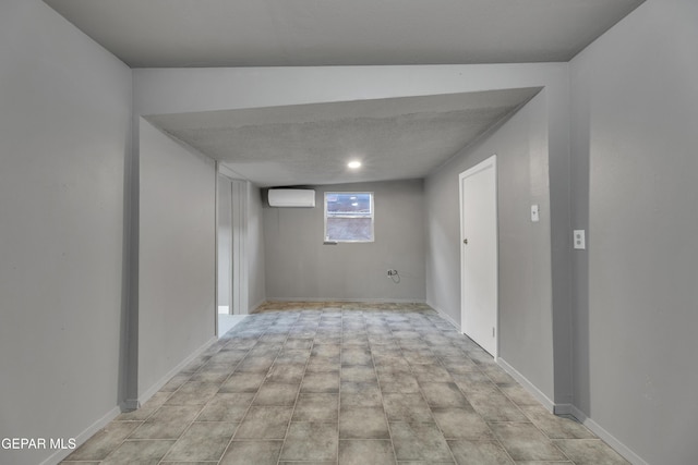 basement with a wall mounted air conditioner and a textured ceiling