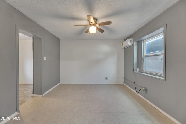 empty room featuring a wall unit AC, ceiling fan, and a textured ceiling