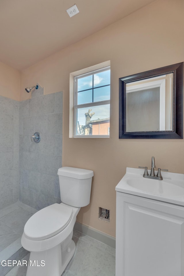 bathroom featuring a tile shower, tile patterned floors, vanity, and toilet