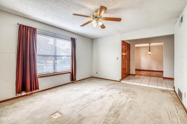 unfurnished room with light carpet, ceiling fan, and a textured ceiling