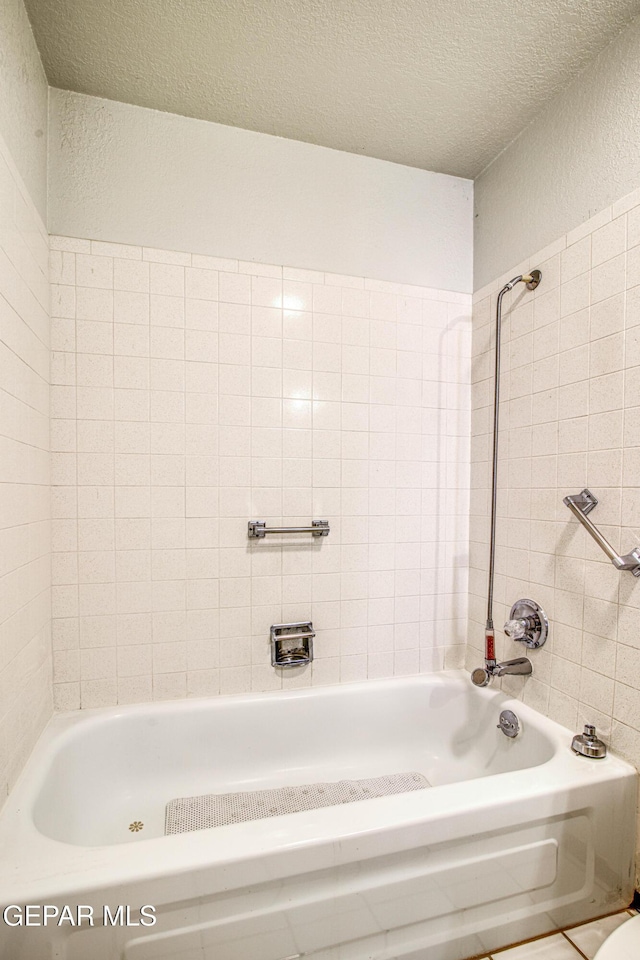 bathroom with tiled shower / bath combo and a textured ceiling