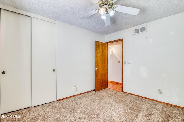 unfurnished bedroom with ceiling fan, a closet, light carpet, and a textured ceiling