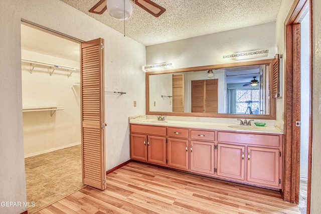 bathroom with vanity, hardwood / wood-style floors, ceiling fan, and a textured ceiling