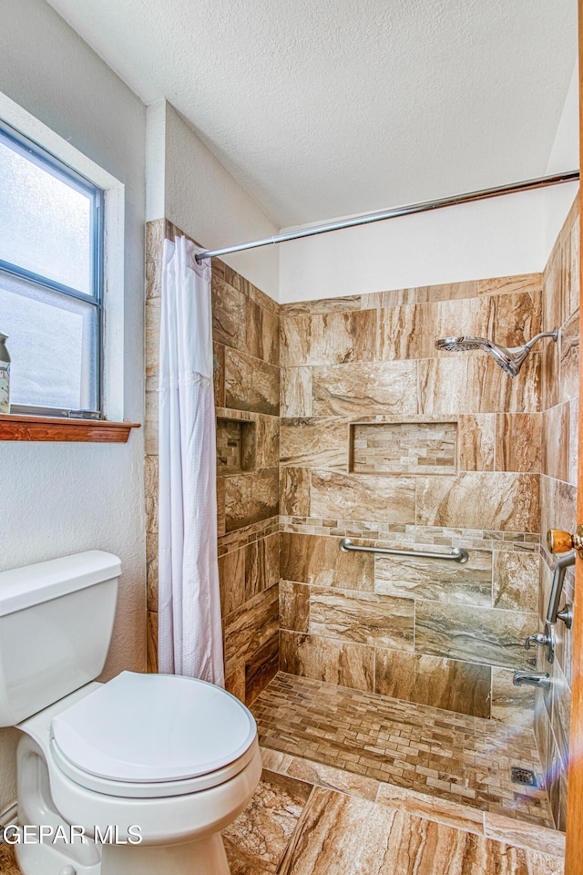 bathroom with toilet, curtained shower, and a textured ceiling