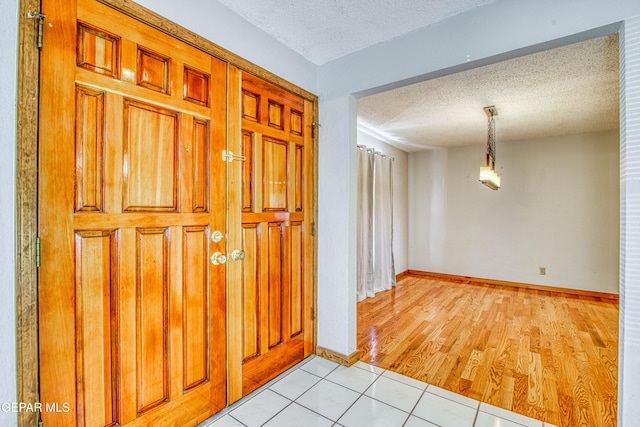 entryway with light tile patterned floors and a textured ceiling