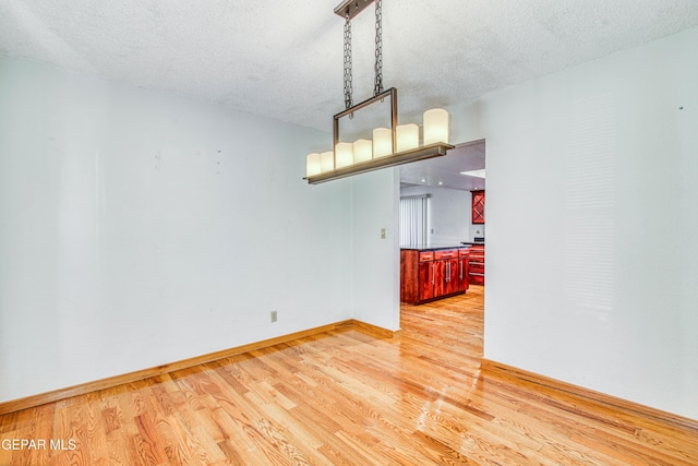 empty room with light hardwood / wood-style flooring and a textured ceiling