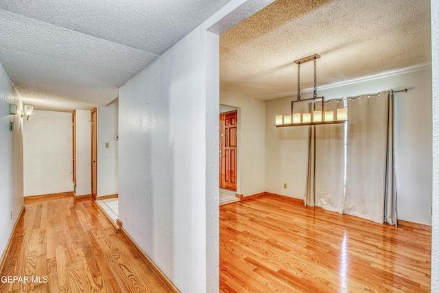 hall with hardwood / wood-style floors and a textured ceiling