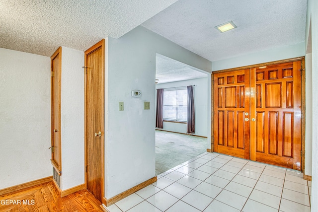 corridor featuring light tile patterned floors and a textured ceiling