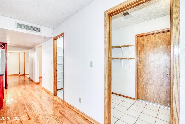 hallway featuring light hardwood / wood-style floors and a textured ceiling