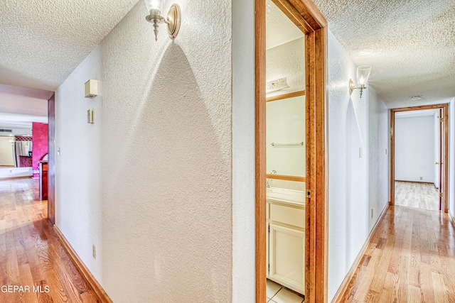 hall featuring a textured ceiling and light hardwood / wood-style flooring