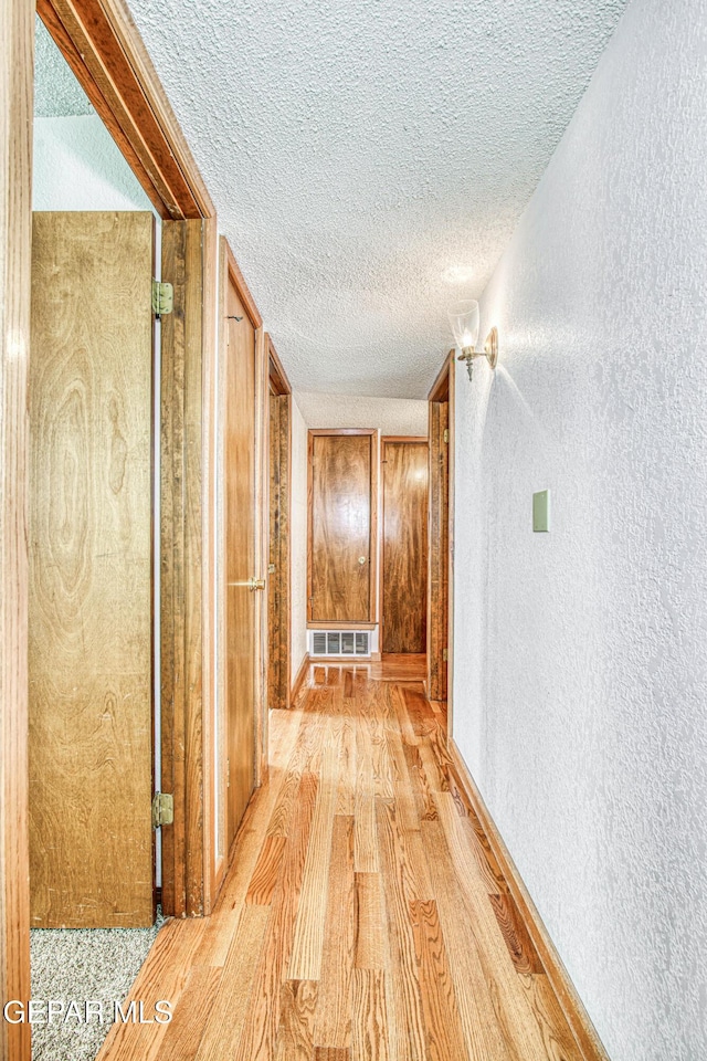 hallway featuring a textured ceiling and light hardwood / wood-style flooring