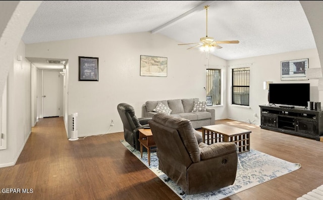 living room with lofted ceiling with beams, ceiling fan, dark wood-type flooring, and a textured ceiling