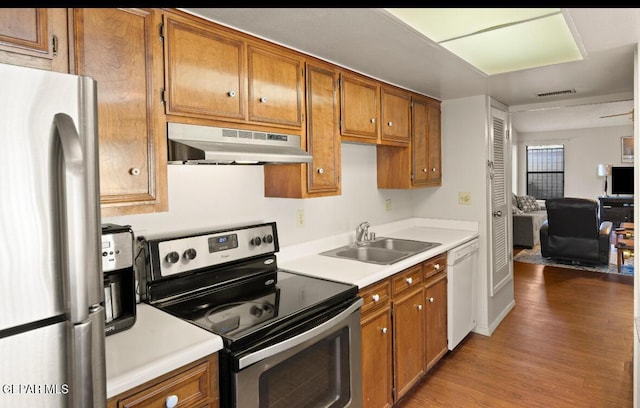 kitchen with sink, light hardwood / wood-style flooring, exhaust hood, and appliances with stainless steel finishes