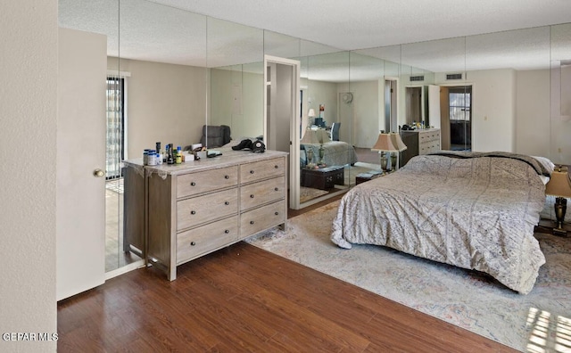 bedroom with a textured ceiling and dark wood-type flooring