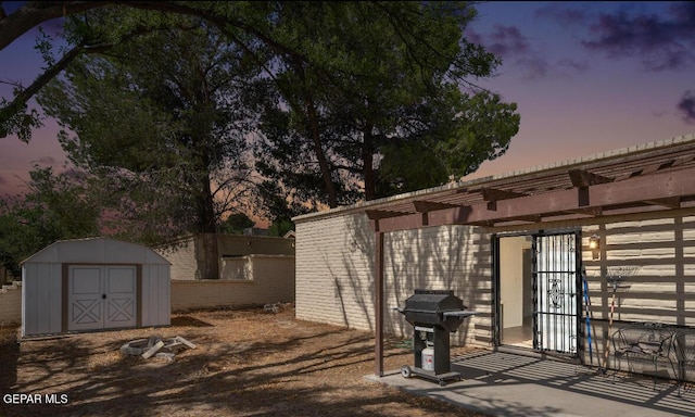 patio terrace at dusk featuring a storage unit and grilling area