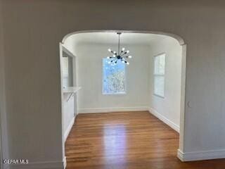 unfurnished dining area featuring hardwood / wood-style floors and a chandelier