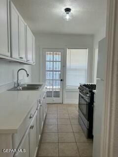 kitchen featuring light tile patterned floors, white cabinetry, stainless steel range with gas cooktop, and sink