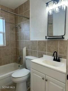 full bathroom featuring tiled shower / bath combo, tasteful backsplash, toilet, vanity, and tile walls