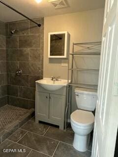 bathroom with vanity, toilet, and a tile shower