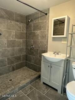 bathroom featuring a tile shower, vanity, and toilet