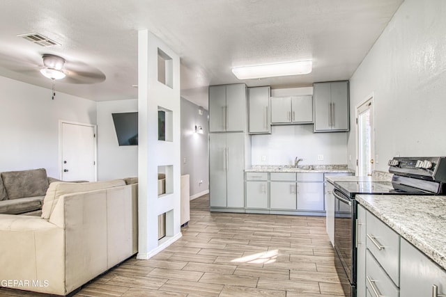 kitchen featuring a textured ceiling, ceiling fan, sink, and black electric range