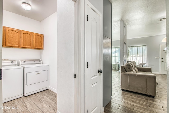 washroom featuring washer and dryer, a textured ceiling, and cabinets