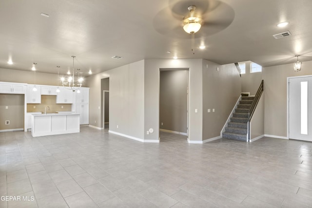 unfurnished living room featuring sink and ceiling fan with notable chandelier