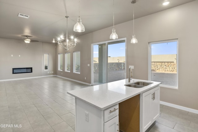 kitchen with white cabinetry, an island with sink, decorative light fixtures, and sink