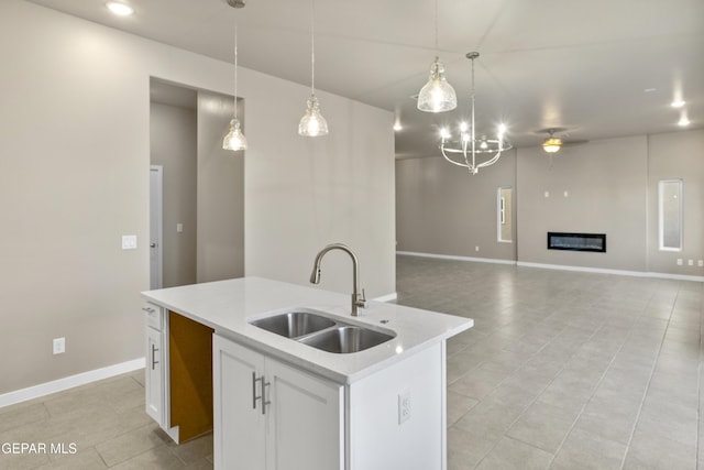 kitchen featuring a center island with sink, white cabinetry, sink, and pendant lighting