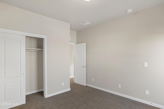 unfurnished bedroom featuring dark carpet and a closet