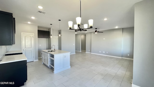 kitchen with decorative light fixtures, sink, light tile patterned flooring, an island with sink, and ceiling fan with notable chandelier