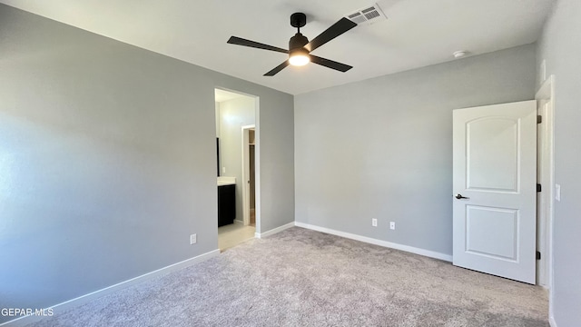 unfurnished bedroom featuring connected bathroom, light colored carpet, and ceiling fan