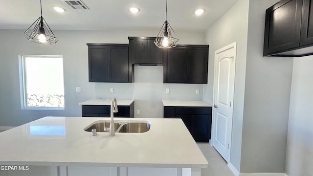 kitchen with a center island with sink, hanging light fixtures, and sink