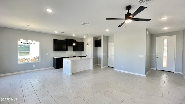 kitchen featuring light tile patterned flooring, sink, ceiling fan with notable chandelier, and a kitchen island with sink