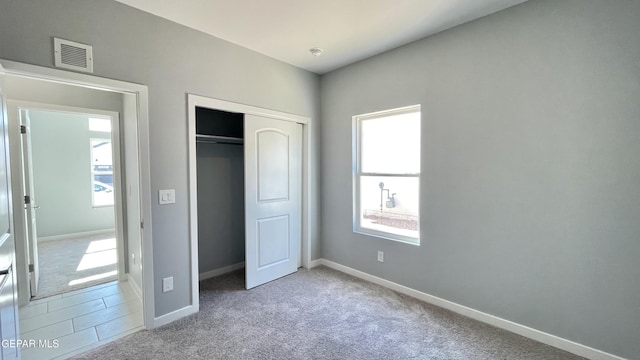 unfurnished bedroom with light colored carpet and a closet