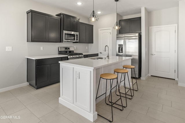 kitchen featuring a kitchen bar, sink, hanging light fixtures, an island with sink, and stainless steel appliances