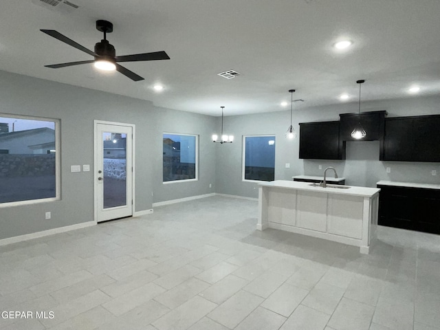 kitchen featuring decorative light fixtures, a kitchen island with sink, ceiling fan with notable chandelier, and sink