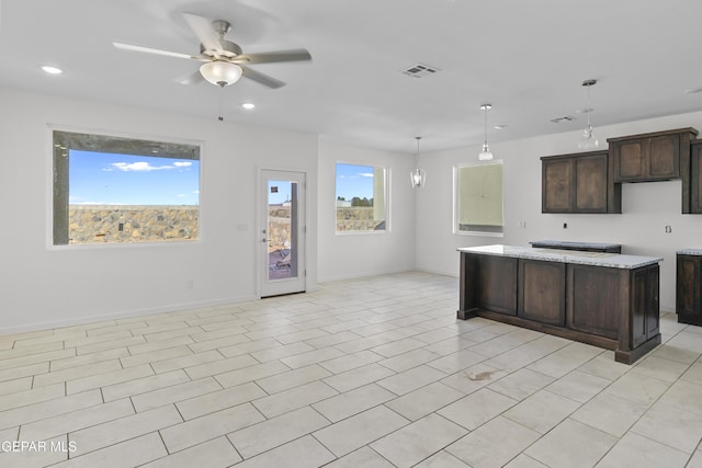 kitchen featuring pendant lighting, light tile patterned floors, ceiling fan, light stone countertops, and dark brown cabinets